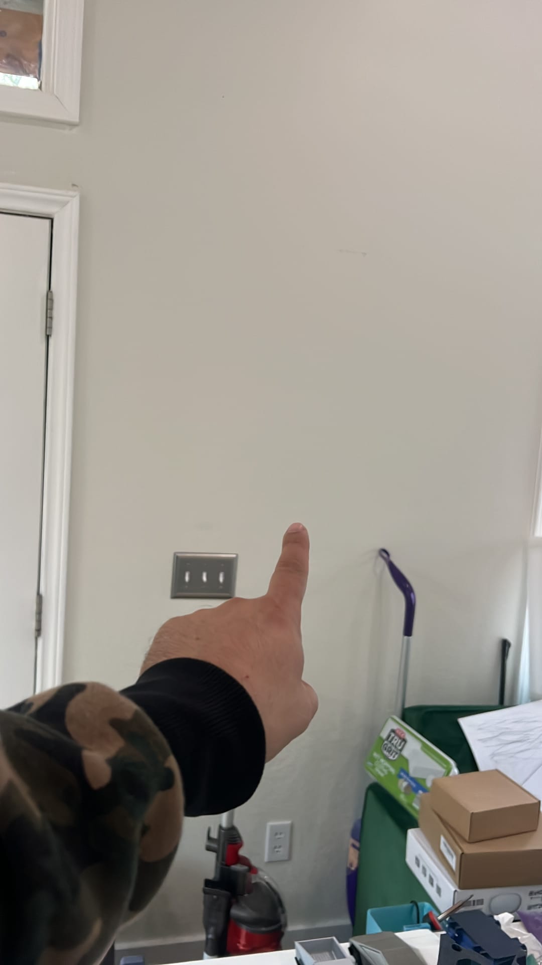 Before — blank wall, Luis pointing at install spot